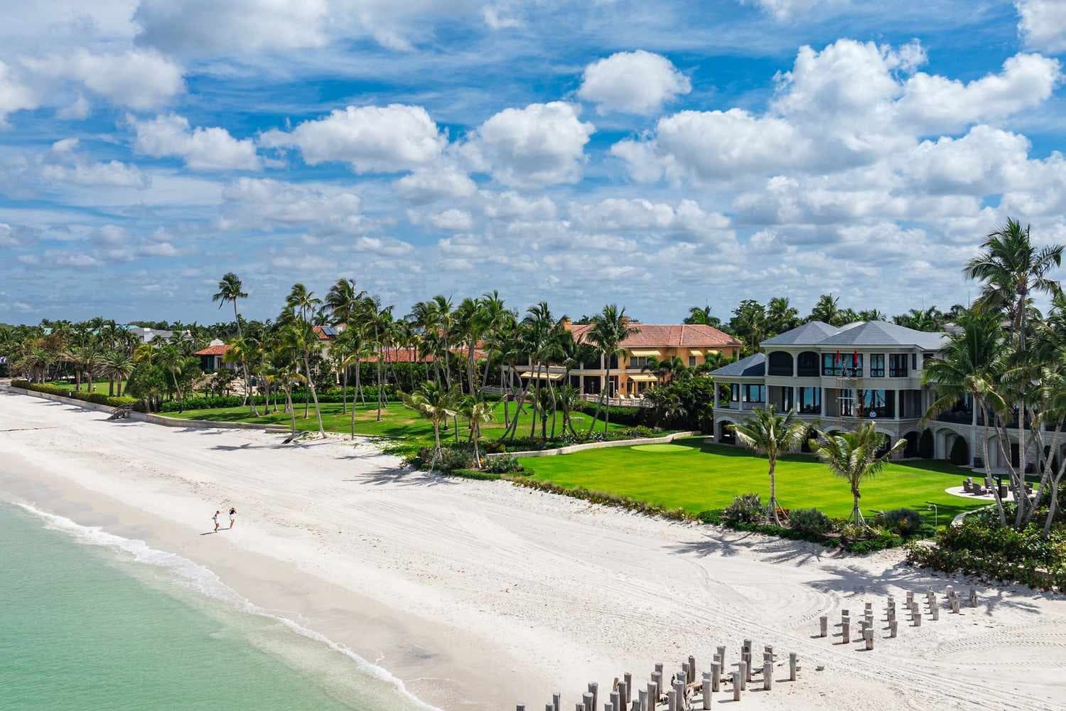 Beachfront estates and palm trees along the Gulf shoreline in Naples, Florida